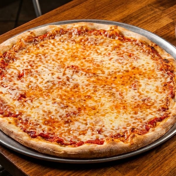 A large, cheesy pizza on a metal tray, with salt and pepper shakers on a wooden table.